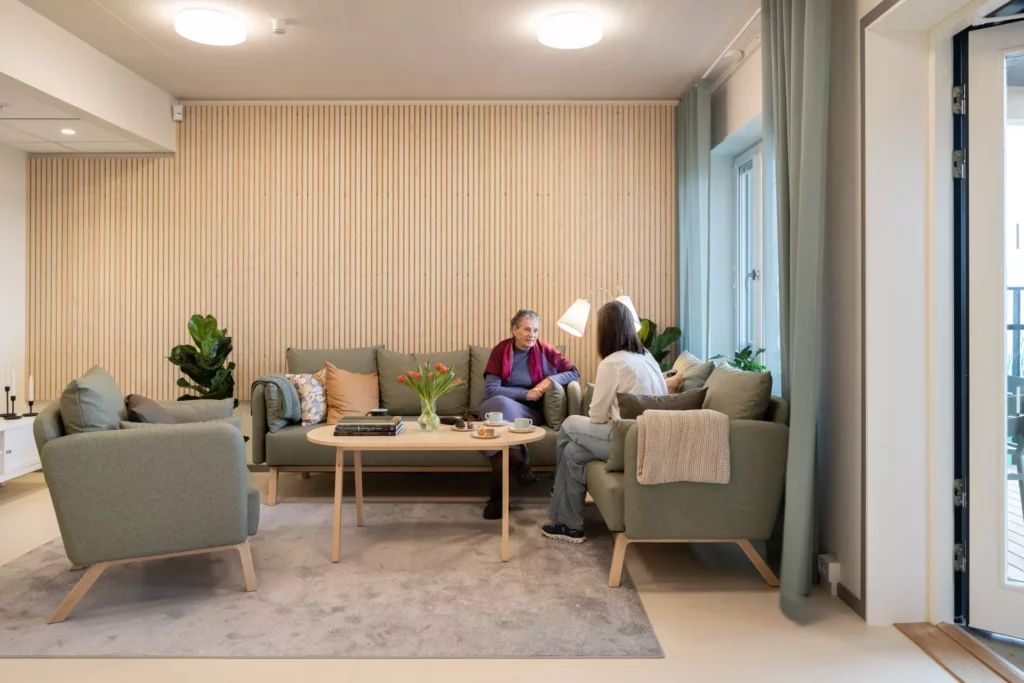 Two people sitting in a cozy sofa talking, in the nursing home Sköndalsvillan in Tyresö.